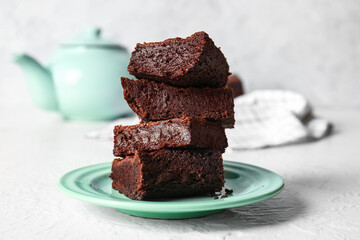 Plate with pieces of delicious chocolate brownie on light background