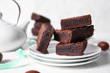 Plates with pieces of delicious chocolate brownie on light background