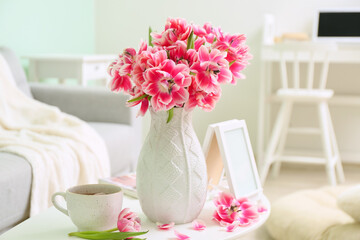 Obraz na płótnie Canvas Vase with beautiful tulips, blank photo frame and cup of tea on table in room. International Woman's Day celebration