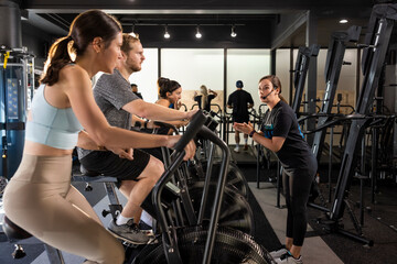 A fitness instructor encouraging her class while they work out on bicycle machines.    