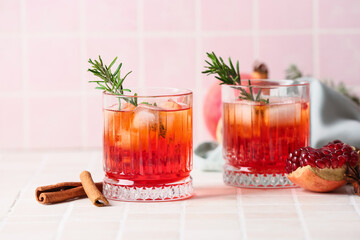 Glasses of tasty pomegranate cocktail on tile background