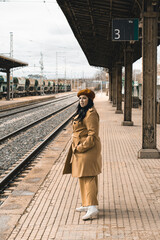 Fat woman with suitcase waiting for the train on the platform