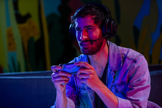 Video game streamer in his room with colored lights and game controller. 