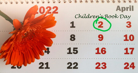 International Children's Book Day, wall-mounted paper calendar with a dedicated date of April 02, 2022 and an orange gerbera flower, top view