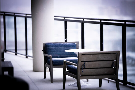 Two patio chairs on the balcony of an apartment rooftop lounge during a snow storm in Dallas, Texas.