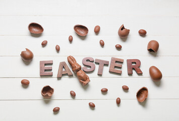 Easter composition with tasty chocolate bunny and eggs on light wooden background