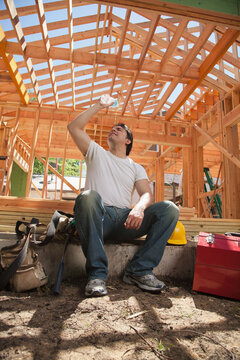Man pouring water over his head while taking a break on a residential construction site