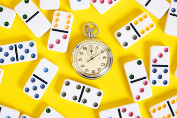 Stopwatch and scattered dominoes on a yellow background. Times up.