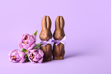 Easter chocolate bunnies and beautiful tulip flowers on lilac background