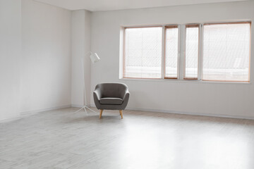 Modern armchair and standard lamp near window in empty room