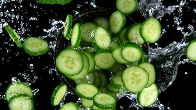 Super slow motion shot of rotating exploded cucumber slices and splashing water on black at 1000fps.