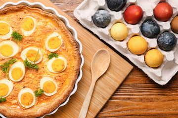 Tasty Easter tart and painted eggs on wooden table, closeup