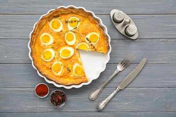 Tasty Easter tart with eggs, spices and cutlery on dark wooden background
