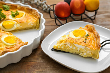 Plate with piece of tasty Easter tart with eggs on wooden background, closeup