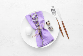 Beautiful table setting with Easter eggs and willow branches on white background