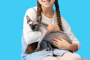 Little girl with Sphynx cat on blue background, closeup