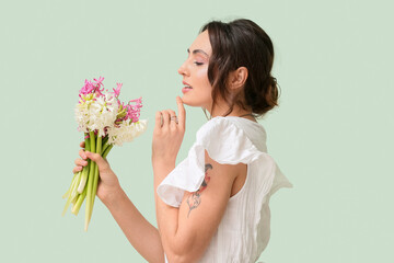 Obraz na płótnie Canvas Pretty young woman with hyacinth flowers on green background