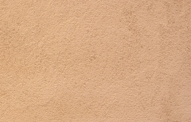 Rough grainy painted sand colored plaster wall background.