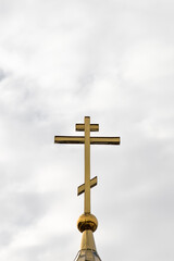 Orthodox cross on the background of a cloudy sky. Vertical photograph of the church cross.