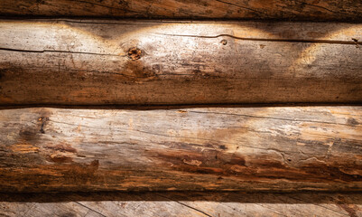 Wooden wall of horizontal weathered logs. Wood texture background with spotlight.
