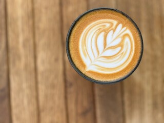 Fototapeta premium A cup of latte art coffee cappuccino on wooden table, flower tree with milk foam