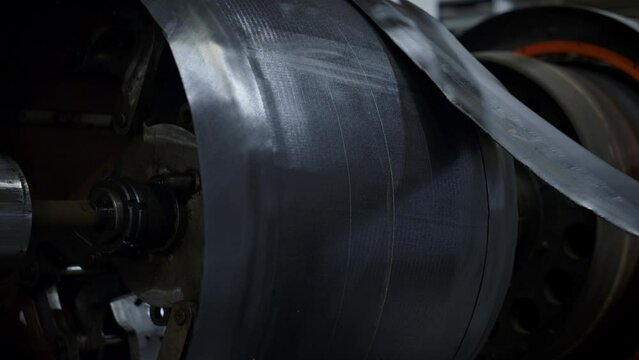 Tyre factory worker hands setting new rubber tape on industrial workshop machine