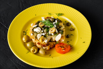 Baked cauliflower steak with chimichurri sauce, almond flakes, capers on a yellow plate. Vegetarian food. Alternative delicious food.