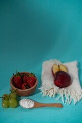 natural fresh red strawberries and apple and green grapes on blue background 