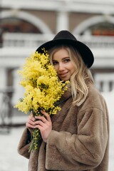 Smiling young woman with mimosa flowers International Women's Day.