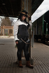 Thick woman dressed in steampunk style in an abandoned train station