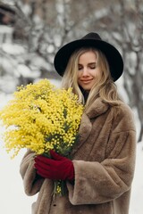 Smiling young woman with mimosa flowers International Women's Day.