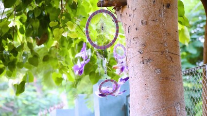 Close up of dream catcher on background of tree leaves with vibrant tone. Hand made. Dreamcatcher feathers flowing in wind. Decoration of home
