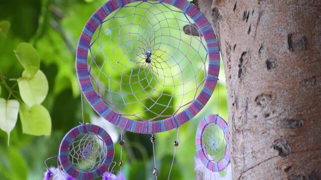 Close up of dream catcher on background of tree leaves with vibrant tone. Hand made. Dreamcatcher flowing in wind
