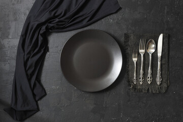 Empty black slate plate on dark stone table. Food background for menu, recipe. Table setting. Flatlay, top view. Mockup for restaurant dish	
