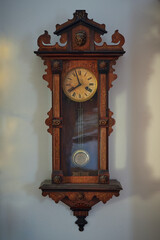 Antique european wall clock: light wall, in interior, lights, shadows, lion, decorated.