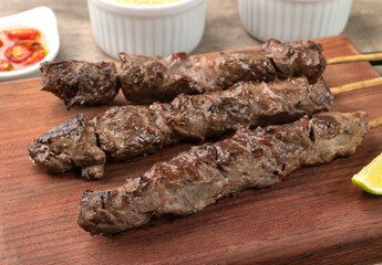 Meat skewers over wooden board with farofa, lemon and pepper