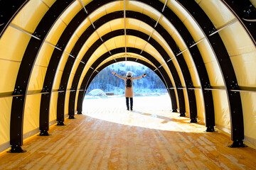 Silhouette of a woman in the sunlight on the background of a wooden arch