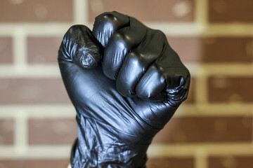 A fist in black medical latex gloves Protects against influenza, viruses and coronavirus. The...