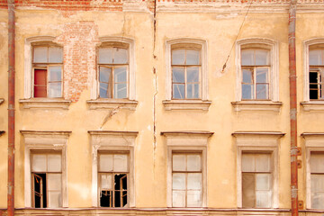 Obraz premium Facade of an old house with broken windows and a crack in the wall
