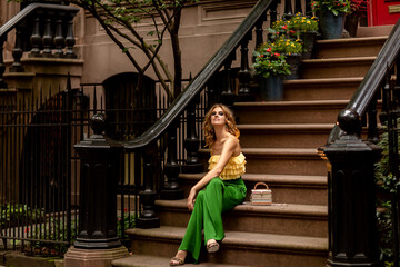 Slim red-haired caucasian young woman in stylish bright yellow top and green trousers elegant...
