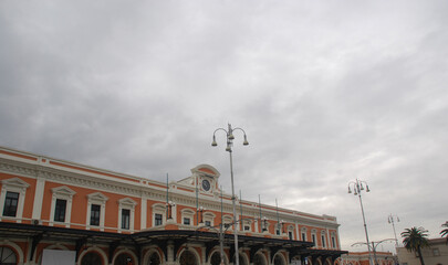Bari, Facciata stazione centrale, orologio, palo della luce, arancio, edificio antico, ferrovia, sud, Puglia, Italia