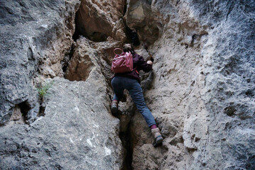 A Caucasian female hiker climbing up the rocky cliff
