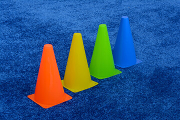 On the blue carpet are red, blue, green and yellow sports cones