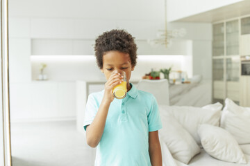 Fototapeta na wymiar Kid boy drinking orange juice at home