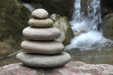 Fototapeta na wymiar Zen stones, pyramid of stones on the background of a waterfall ... 