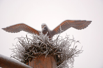 Wooden figurine of a crow covered with eagle in the yard of a house
