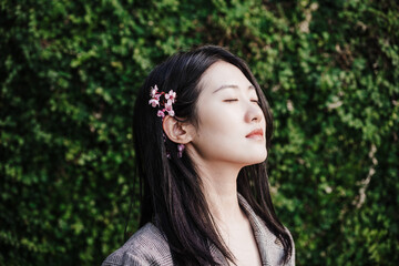 Naklejka premium portrait of beautiful chinese asian woman with eyes closed and almond tree flowers.Spring time,relax
