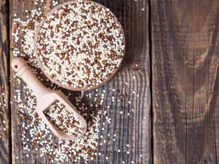Quinoa in wooden bowl and scoop on rustic background