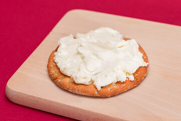 Crispy Cracker Sandwich with Cream Cheese on Wooden Cooking Board on Magenta Background