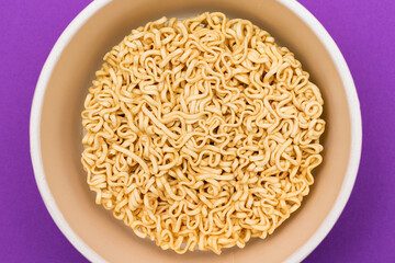 Opened Package with Uncooked Instant Noodles on Violet Background. Raw Pasta. Dry Asian Fast Food. Quick Lunch